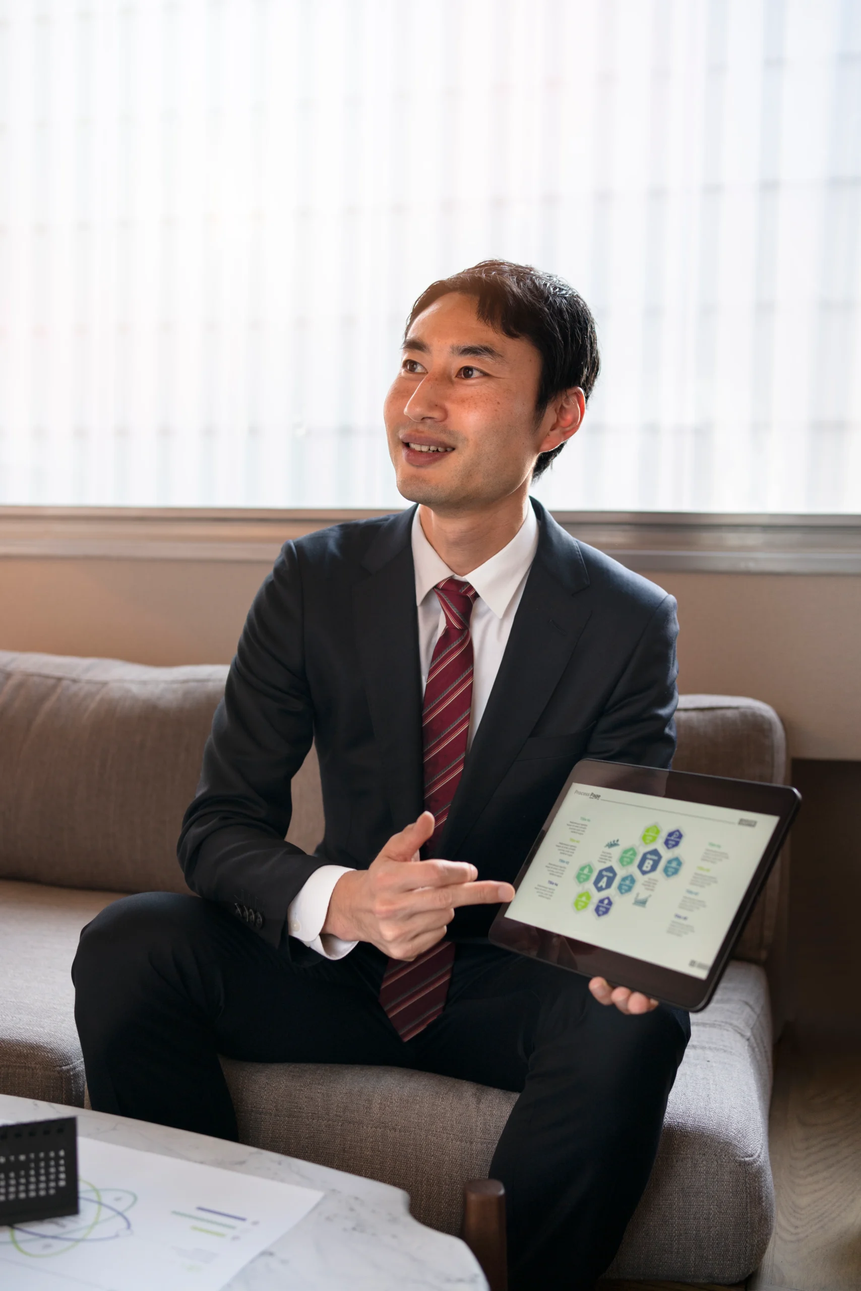 A smiling business professional presenting a customer experience framework diagram on a tablet, illustrating how Feedback ASAP's connected solution translates insight into clear team priorities, action plans, and measurable growth outcomes.