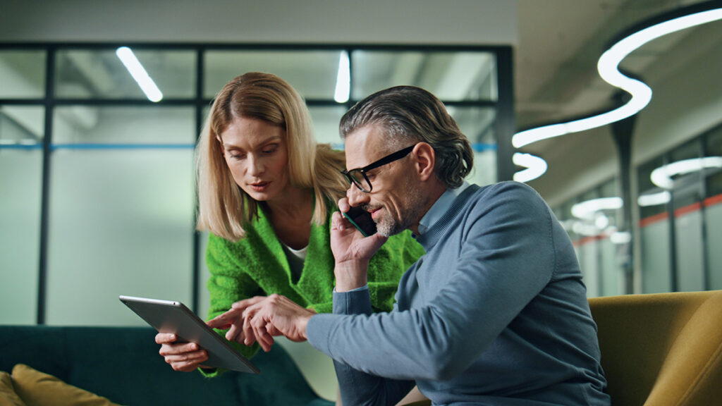 AI in CX growth programs: colleagues reviewing customer data on a tablet before acting on it